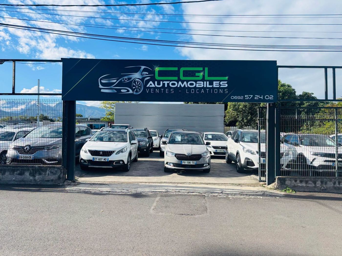 Le parc CGL Automobiles à Pierrefonds : enseigne, Peugeot 2008, Skoda Fabia et 3008 alignés devant les montagnes